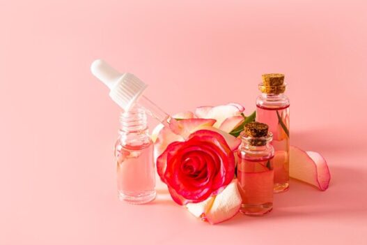 Rose water skin care bottle surrounded by fresh rose petals